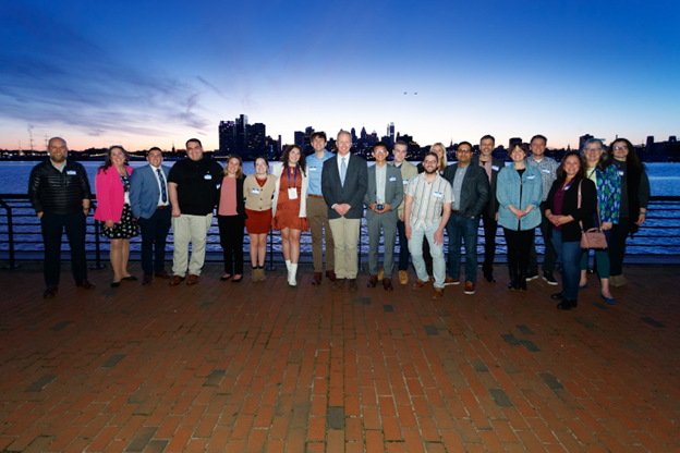Students and faculty posing in front of a backdrop of Delaware River and Philly