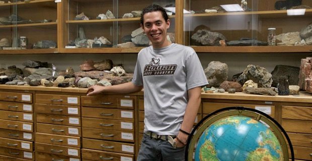 student in front of fossils in classroom