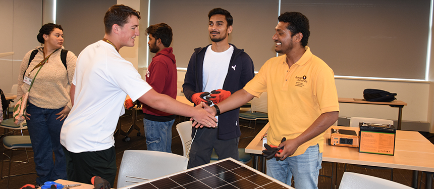 kids shaking hands while working with solar panels
